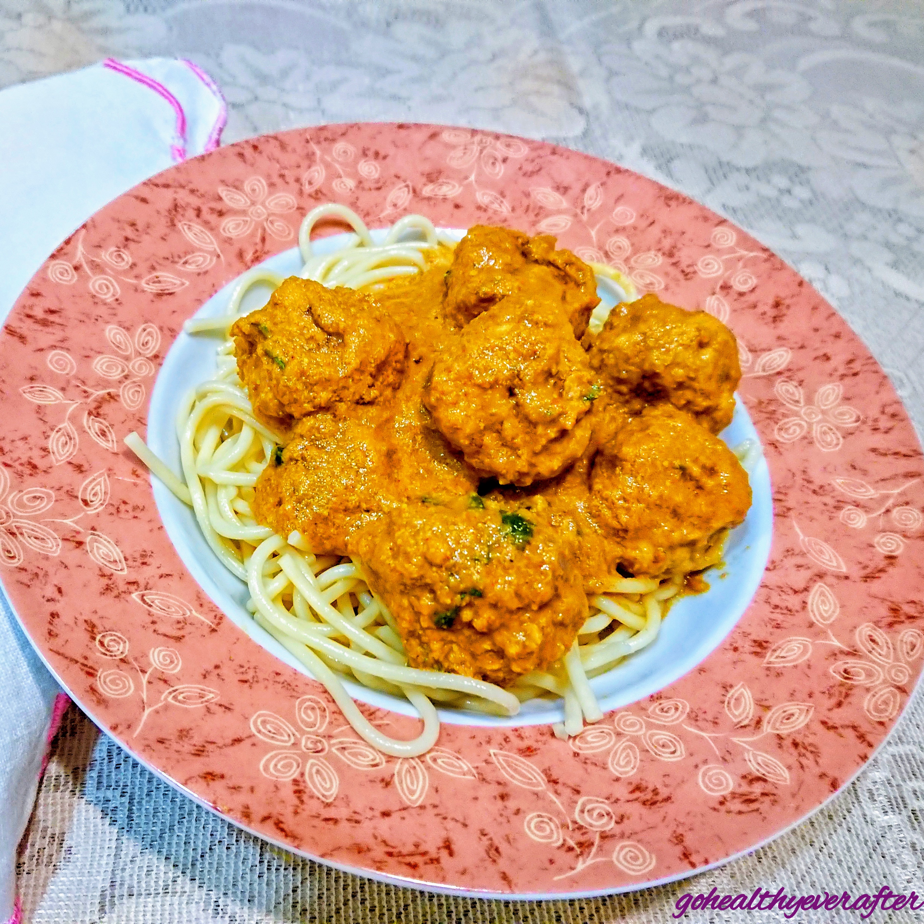 close-up view of chicken meatballs in curry sauce on spagetti